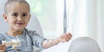 A young boy sits in a chair as he receives his chemotherapy treatment intravenously.