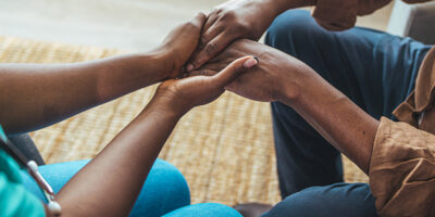 Male patient holding hands with a nurse.